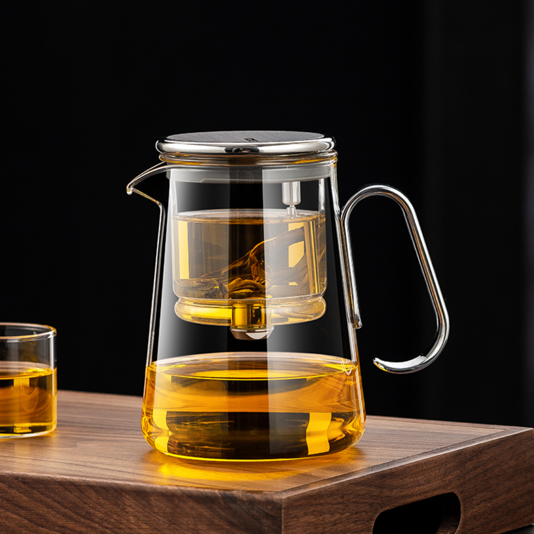 Clear glass teapot with silver handle and lid, filled with tea