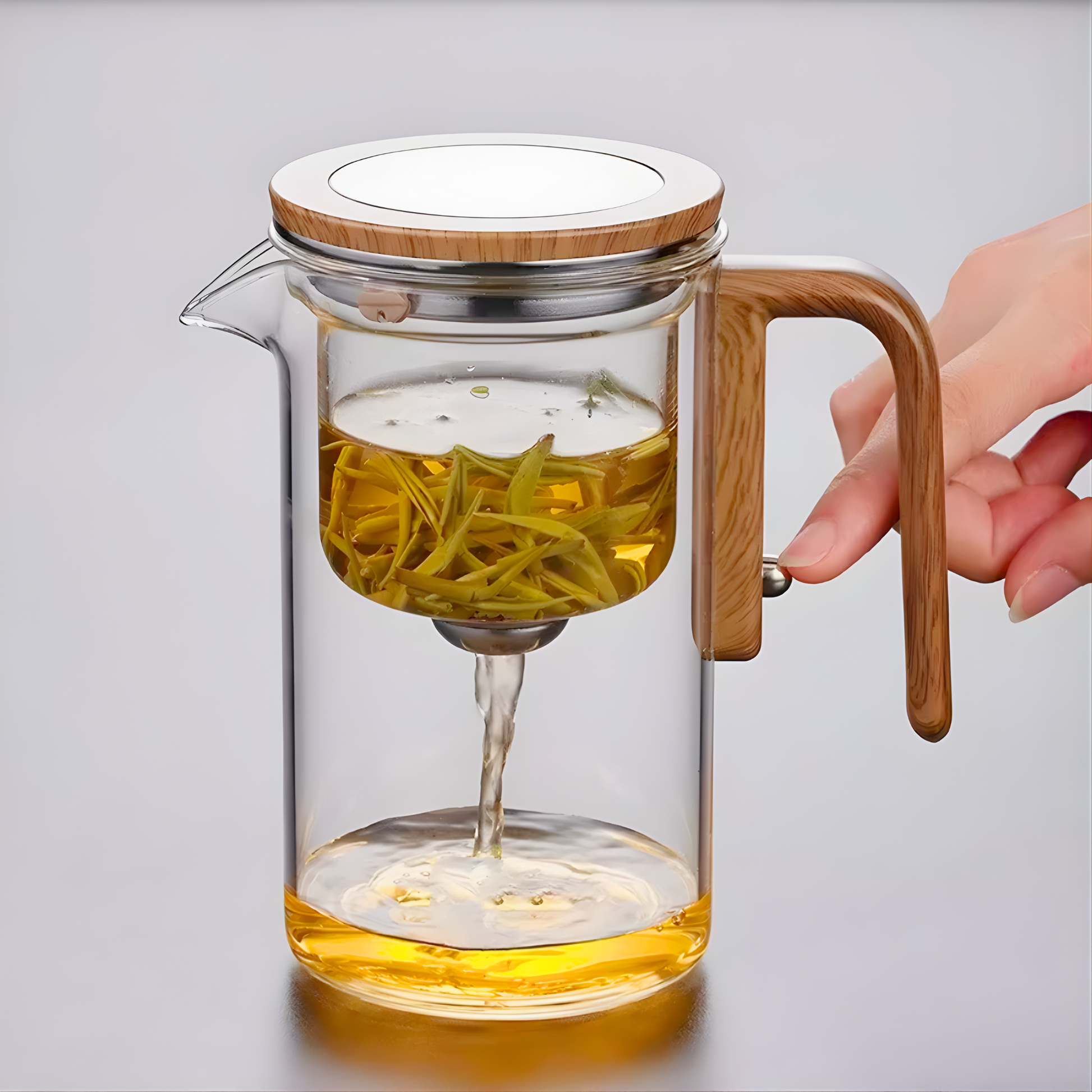 Glass teapot with wooden handle and lid filled with tea