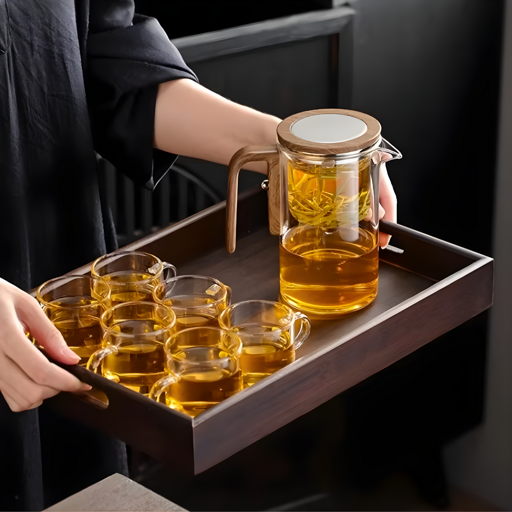 Clear glass teapot with cups, filled with tea